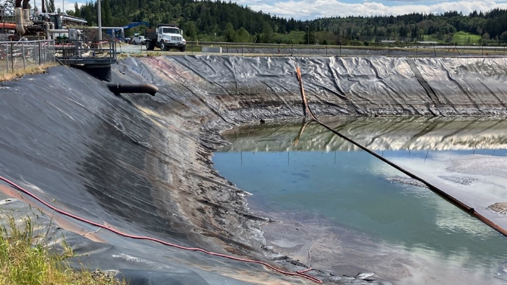 Portion of an artificial pond lined with plastic and partially filled with liquid.